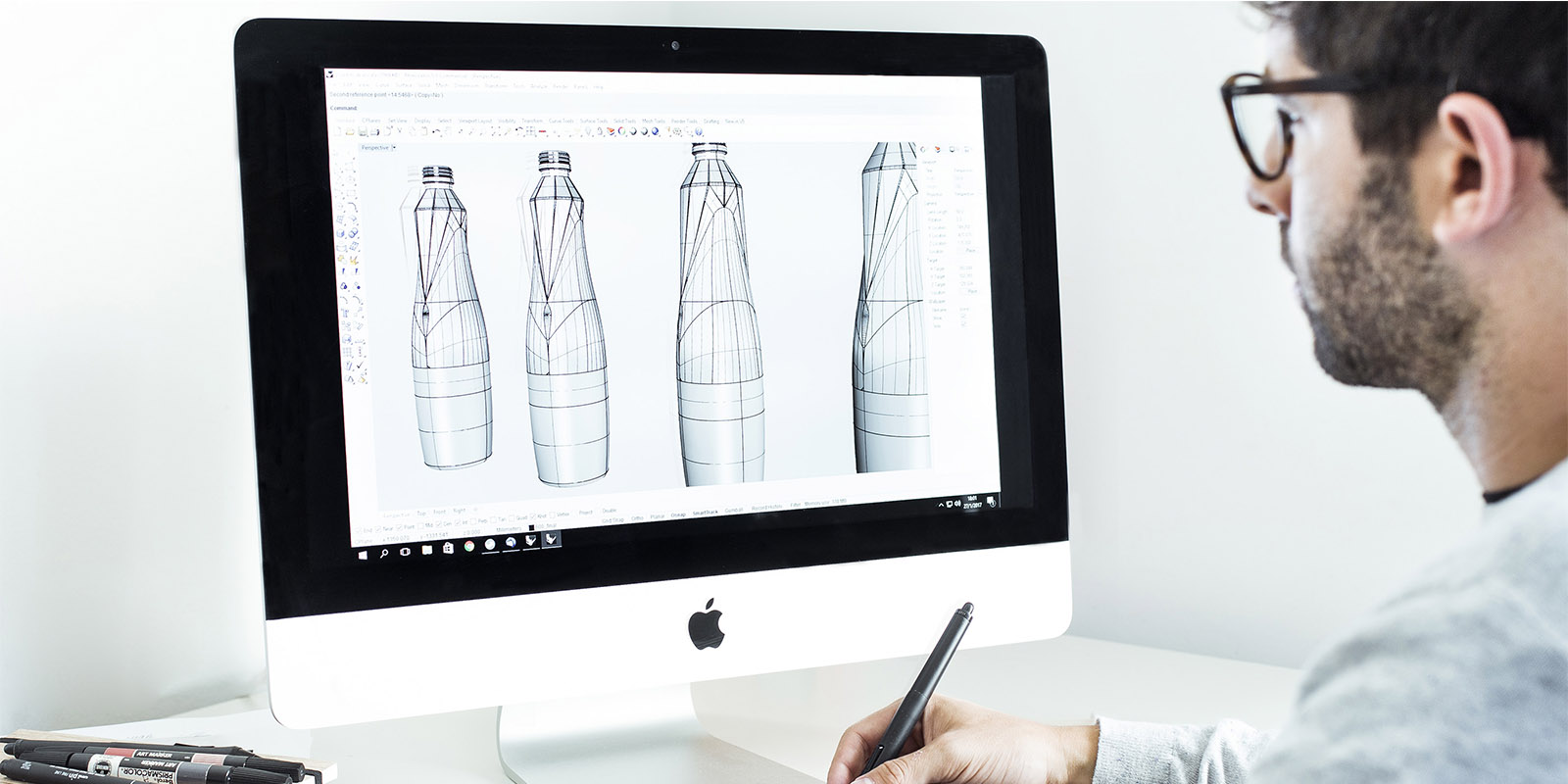 Un hombre está diseñando una botella facetada de agua Gond Wana en una computadora, diseño de packaging por Tridimage.