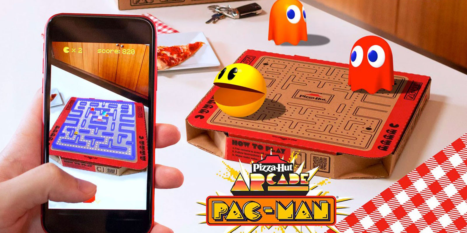 Juego de PAC-MAN ARCADE en realidad aumentada sobre una caja de pizza con el laberinto de PAC-MAN impreso. Incluye los personajes del juego y el logo de Pizza Hut.”