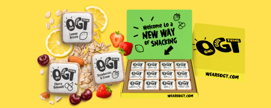 Caja de snacks saludables OGT con packaging eco-friendly: caja amarilla abierta con tapa verde en su interior que dice “Welcome to a NEW WAY OF SNACKING”, junto a ilustraciones de frutas. En el interior, hay doce snacks individuales OGT con distintos sabores, como banana con mantequilla de maní y banana con cereza. El empaque es amarillo y tiene la web “WEAREOGT.COM” impresa.