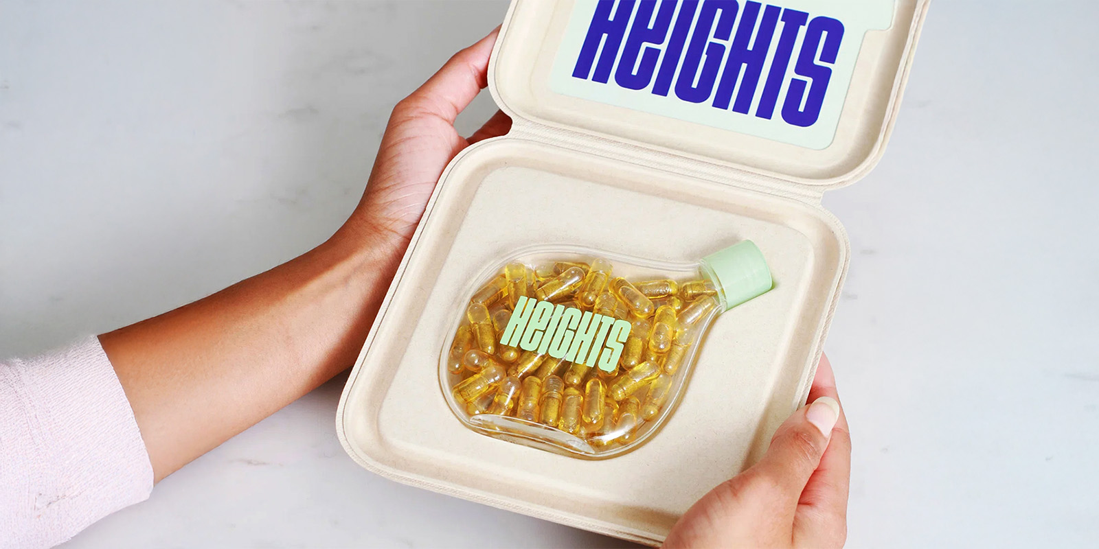 Caja sustentable de e-commerce con botella de suplementos Heights Brain Health: caja ecológica marrón con diseño minimalista, contiene una botella de suplementos Heights Brain Health. El empaque resalta ingredientes clave para la salud cerebral y un enfoque de nutrición consciente.