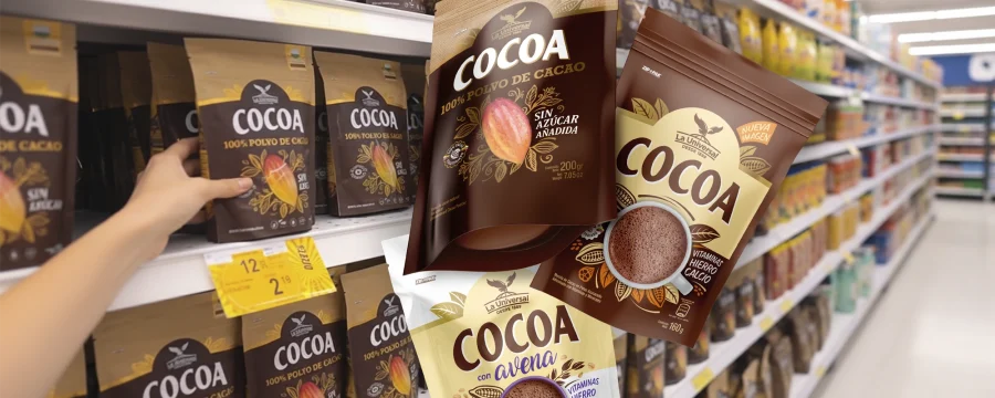 Estante de supermercado con variedad de productos Cocoa La Universal, incluyendo opciones con avena, canela y sin azúcar añadida. El diseño de packaging por Tridimage destaca ilustraciones de vainas de cacao y tonos premium cálidos que refuerzan el origen natural y la calidad del cacao.