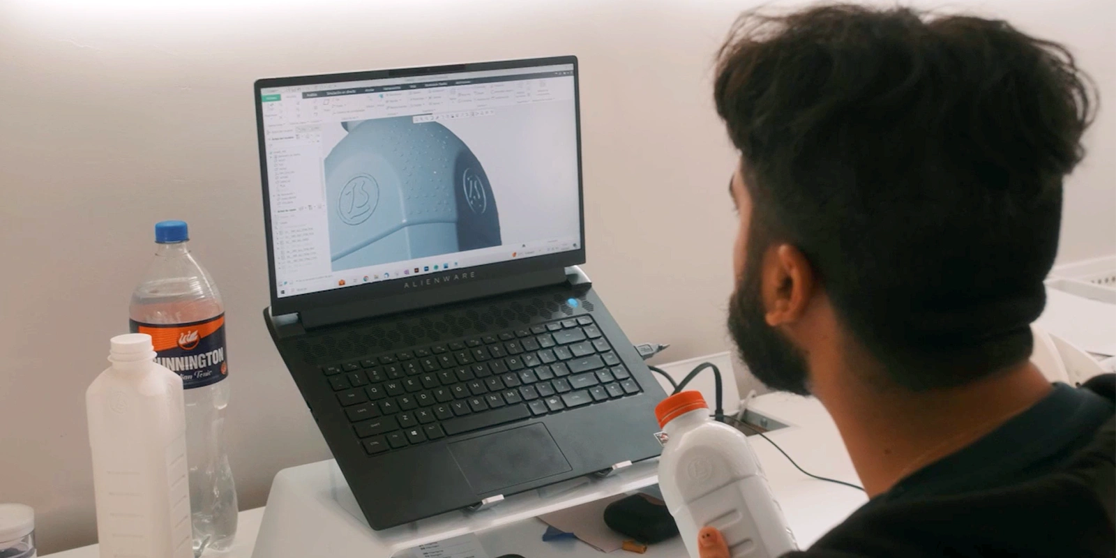 Diseñador trabajando en la visualización 3D y modelado de la nueva forma de la botella de leche. Diseño estructural por Tridimage.