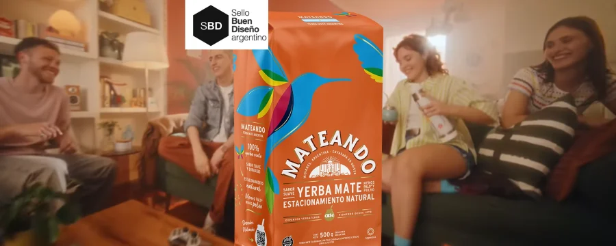 Grupo de jóvenes riendo y compartiendo un mate en una sala de estar, con un paquete de yerba Mateando en primer plano, destacando su diseño colorido y natural. Diseño de packaging por Tridimage. Sello Buen Diseño Argentino