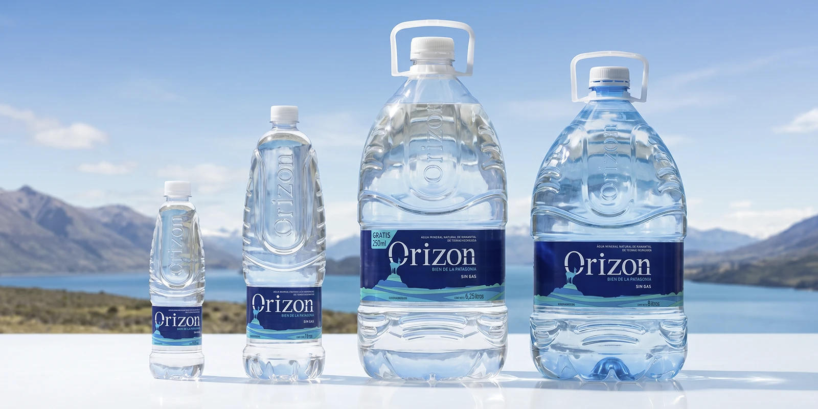 Diferentes tamaños y formatos de botellas y bidones de agua de manantial Orizon con fondo de paisaje patagónico.