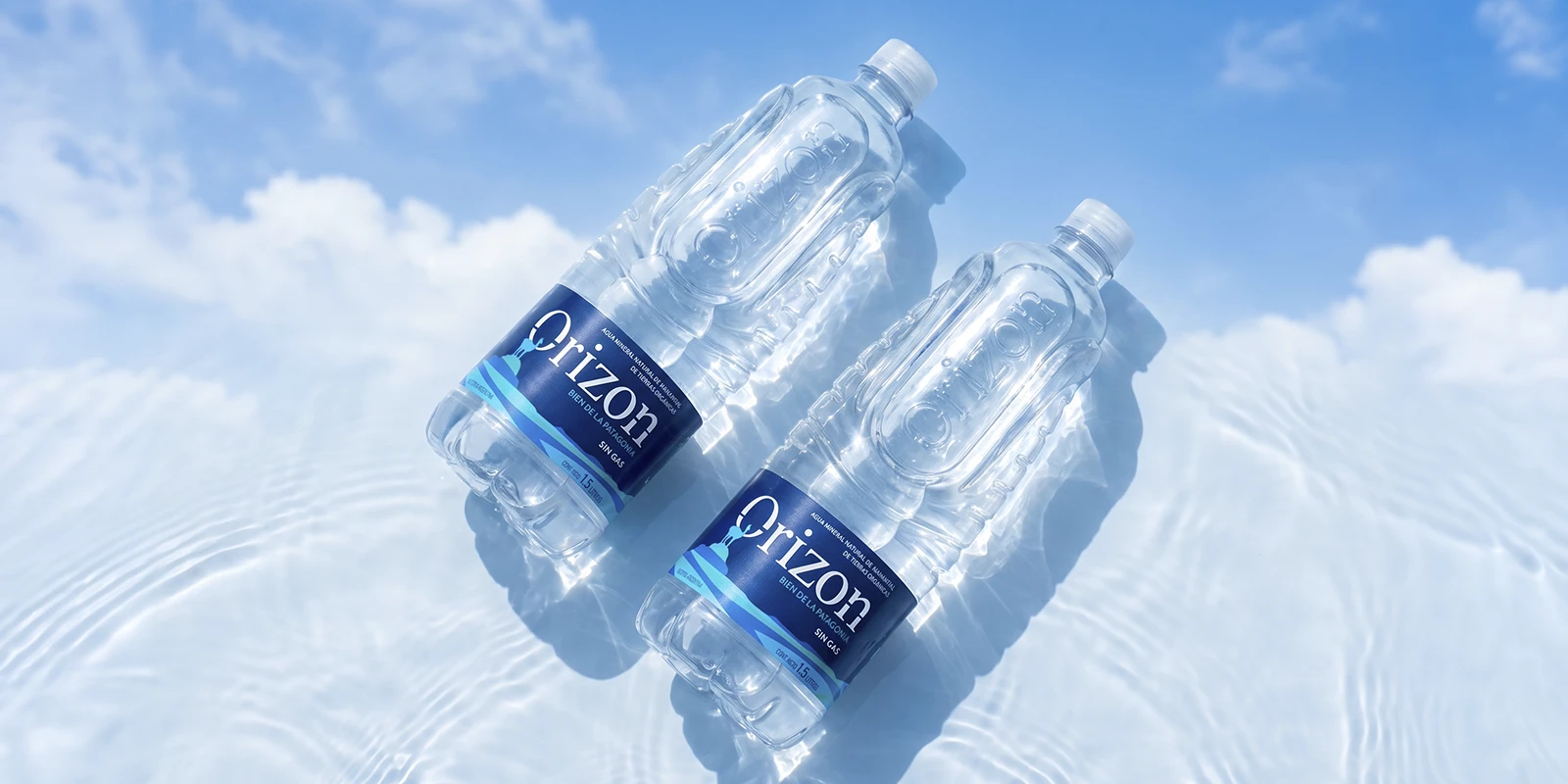 Dos botellas de agua mineral Orizon de perfil sobre una superficie de agua cristalina con reflejos celestes.