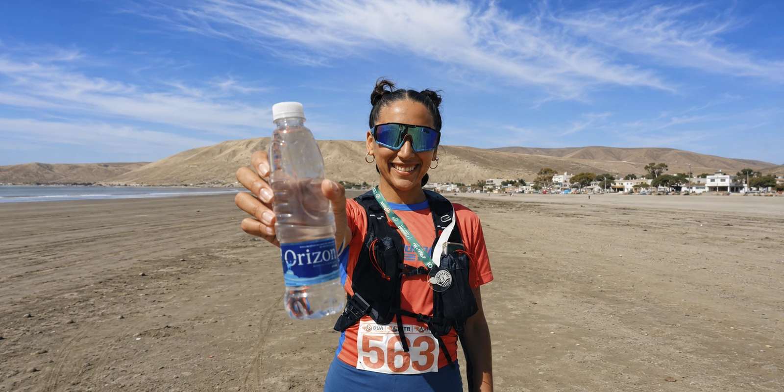 Mujer con indumentaria deportiva sostiene botella de agua mineral orizon