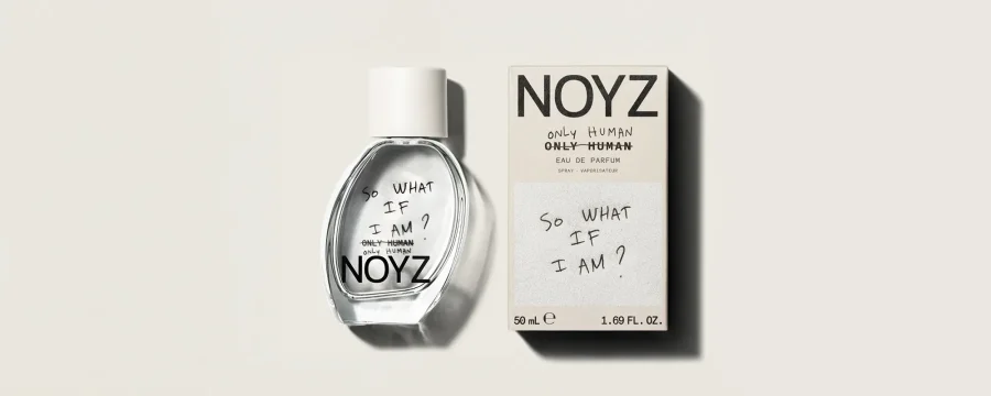 Perfume NOYZ Only Human junto a su caja, con diseño minimalista en blanco y negro y la frase manuscrita “So what if I am?