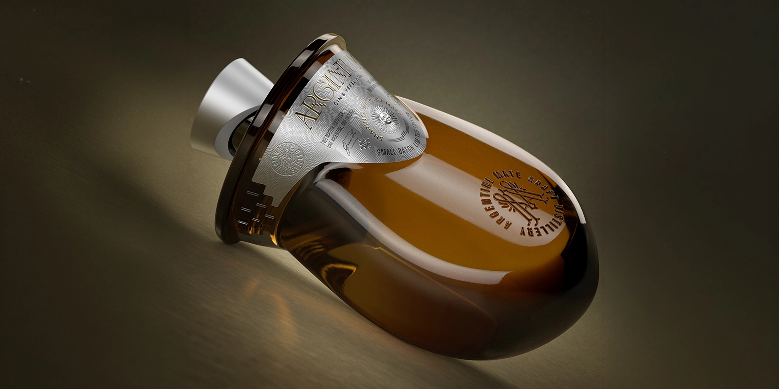 Botella de vidrio ámbar Argintum recostada, mostrando la etiqueta metálica con relieve diseñada por Tridimage.